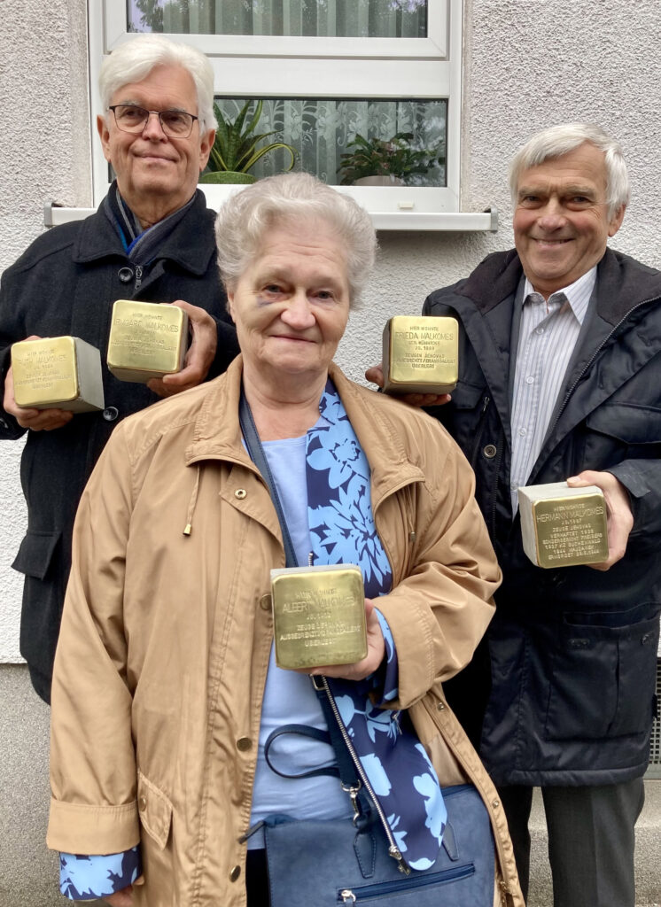 Foto der drei Enkelkinder von Frieda und Hermann Malkomes, Hans-Michael Künz (von links), Maria Haaring und Thomas Künz bei der Stolperstein-Verlegung mit Stolpersteinen in der Hand.