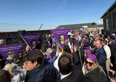 Teilnehmer an der Gedenkfeier "Niemals wieder!" zum 80. Jahrestages der Befreiung des KZ Mauthausen vor einem Denkmal.