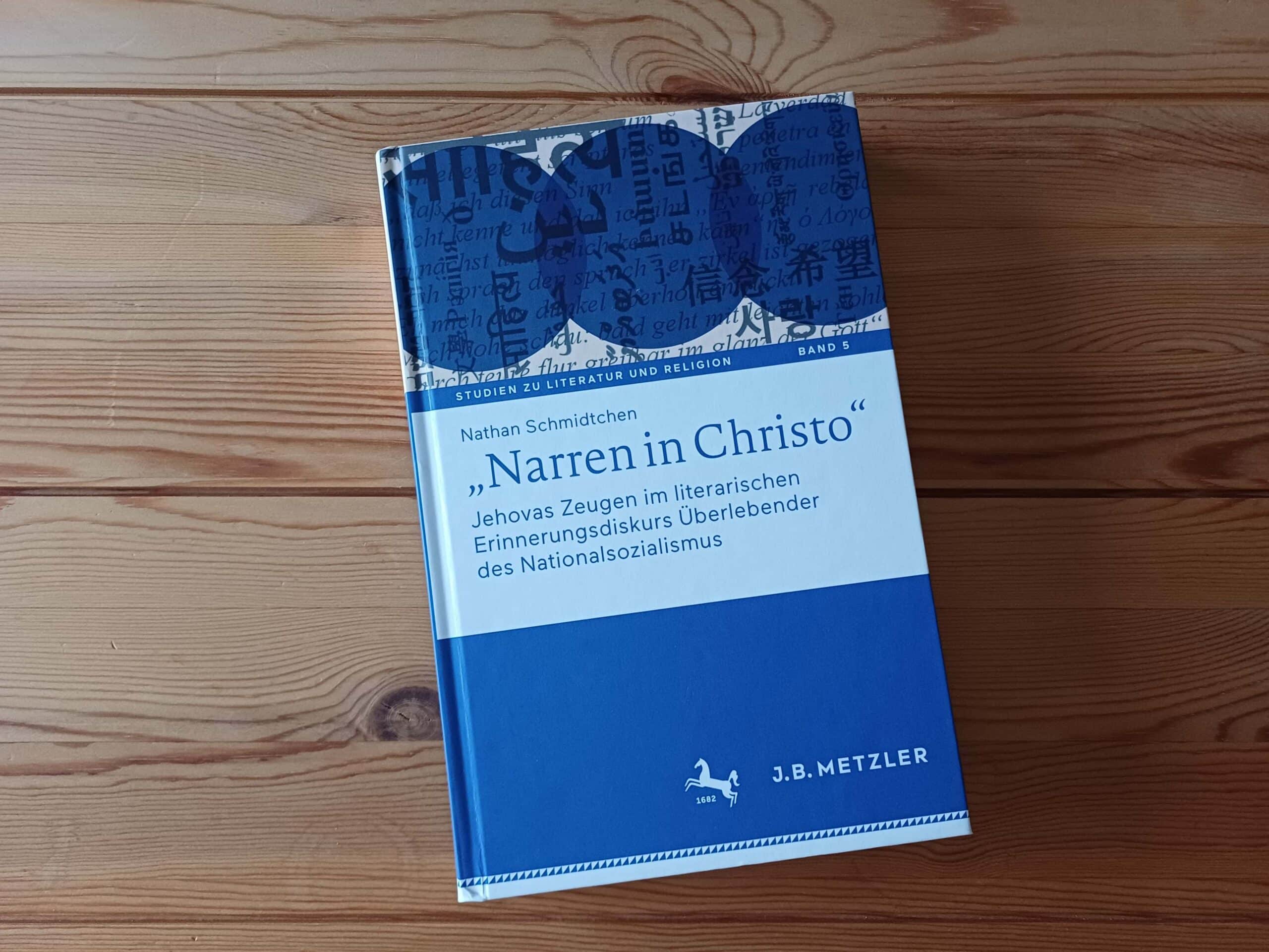 Le livre bleu « Narren in Christo » de Nathan Schmidtchen posé sur une table en bois.